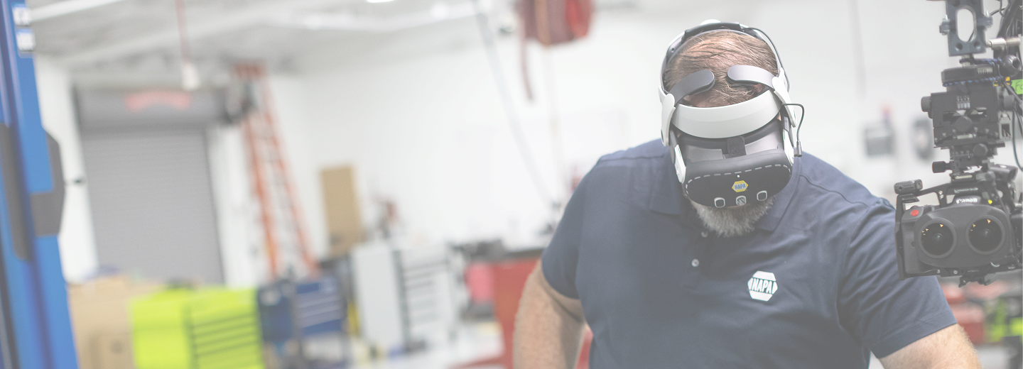 Automotive technician wearing a virtual reality headset beside an engine in a workshop during immersive training.